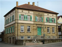 Das Foto basiert auf dem Bild "Altes Schulhaus (1872)" aus dem zentralen Medienarchiv Wikimedia Commons und der Creative Commons "Namensnennung-Weitergabe unter gleichen Bedingungen 3.0 Unported"-Lizenz veröffentlicht. Der Urheber des Bildes ist Peter Schmelzle.