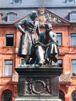 Das Foto basiert auf dem Bild "Denkmal der Brüder Grimm in Hanau" aus dem zentralen Medienarchiv Wikimedia Commons. Diese Bilddatei wurde von ihrem Urheber zur uneingeschränkten Nutzung freigegeben. Diese Datei ist damit gemeinfrei („public domain“). Dies gilt weltweit. Der Urheber des Bildes ist Steschke.